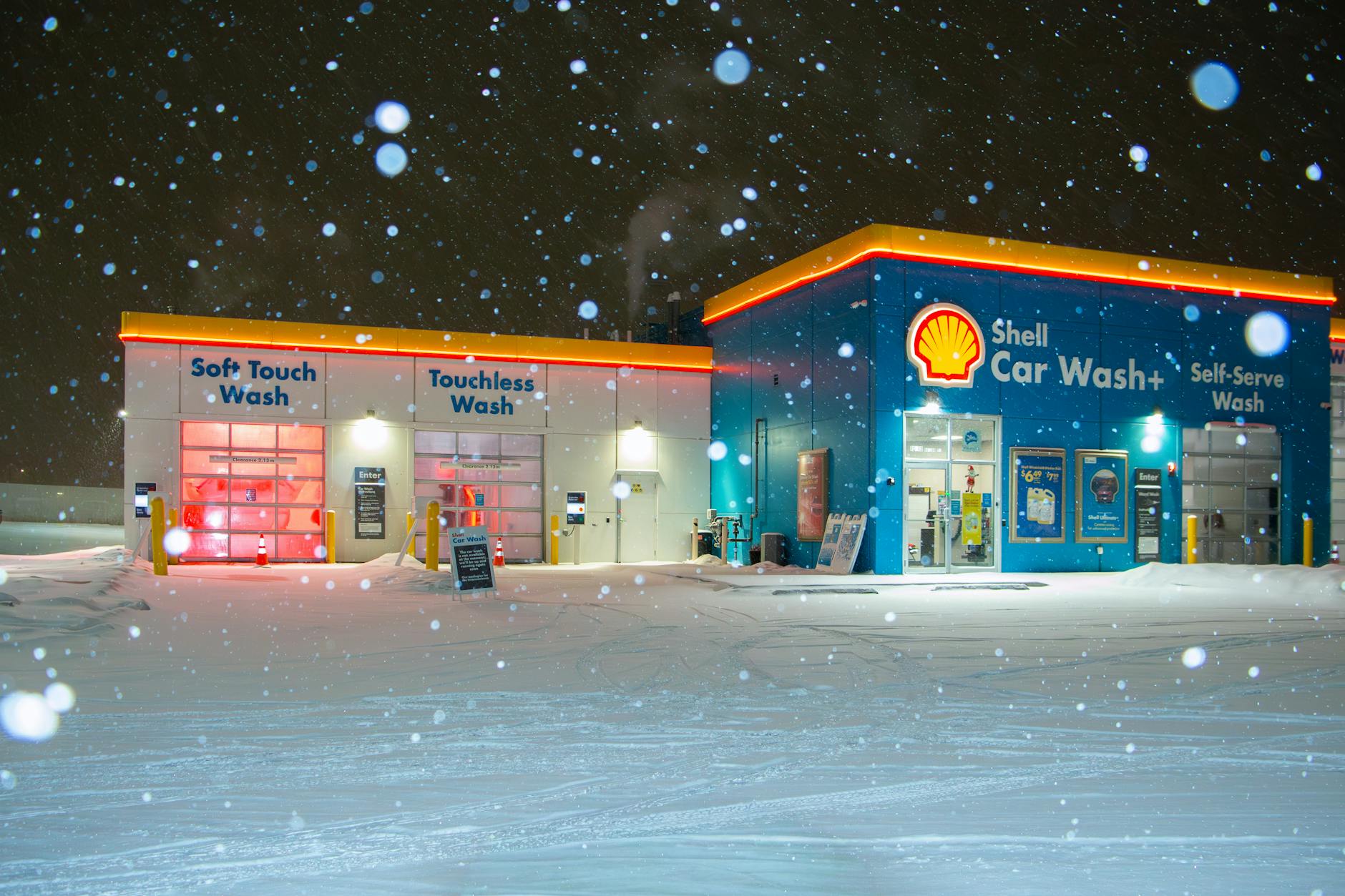 Samochód w myjni automatycznej nocą podczas intensywnych opadów śniegu