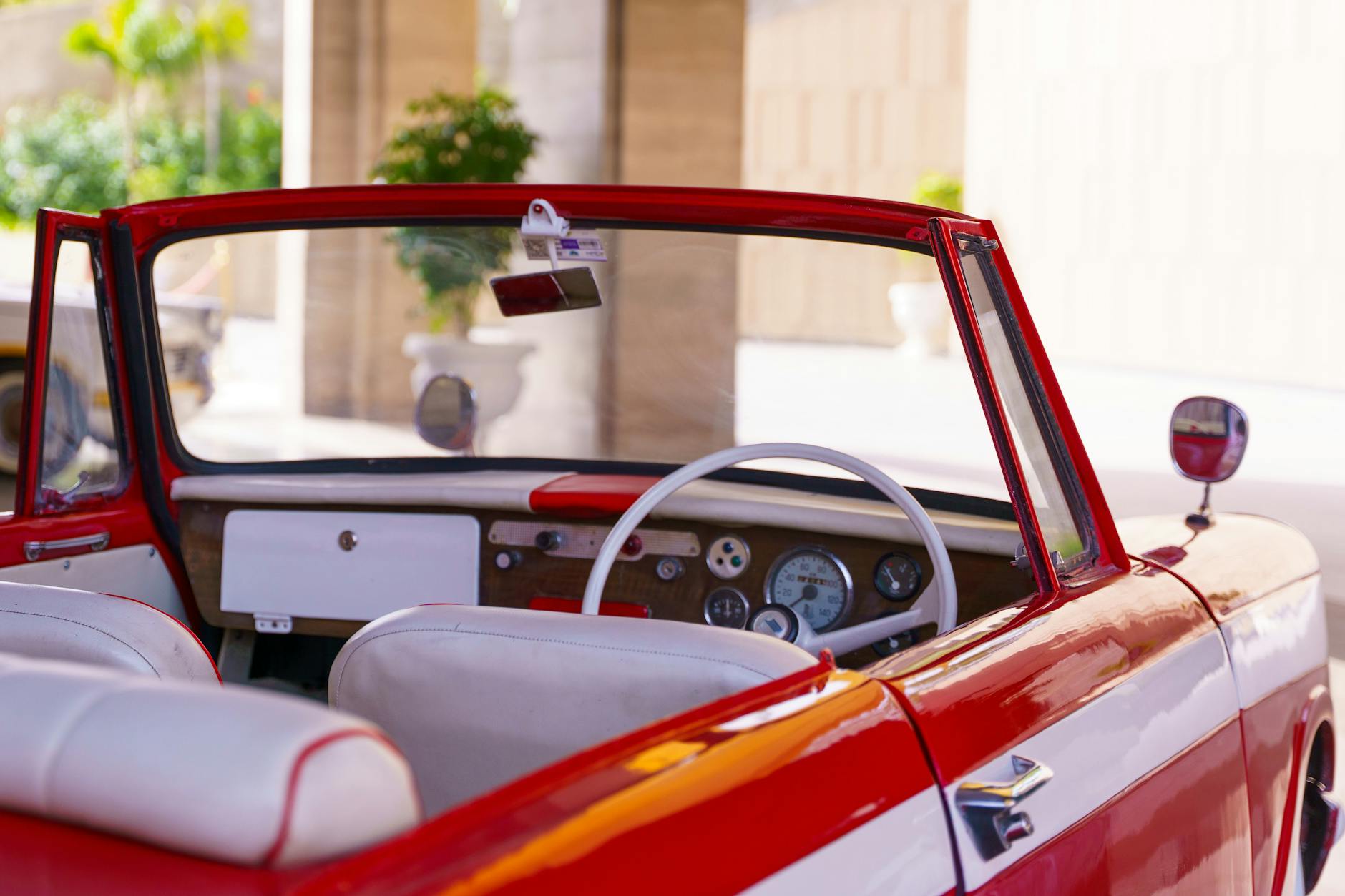 Wnętrze klasycznego czerwonego cabrio z jasną tapicerką i deską retro