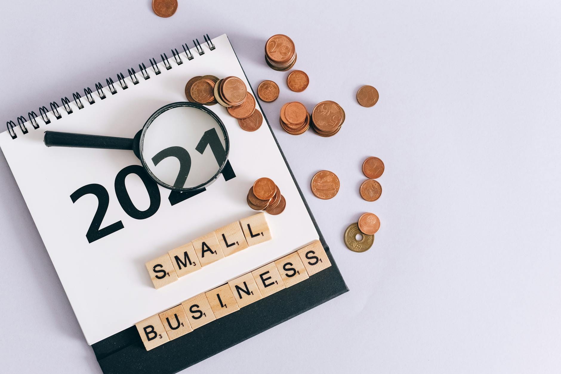 Kalendarz 2021, monety, lupa i napis small business ułożone na biurku